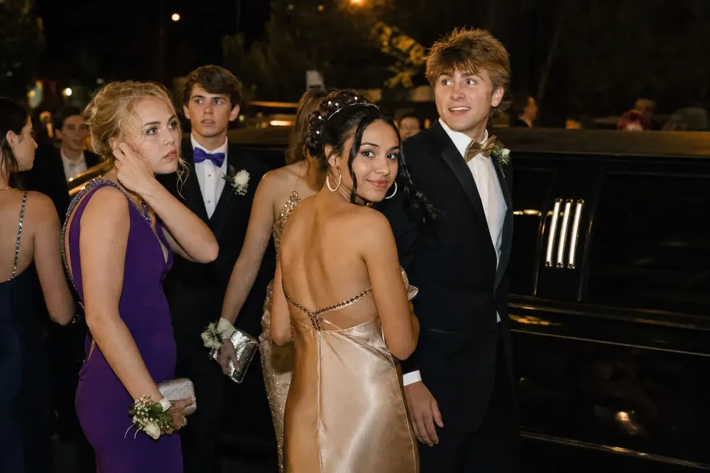 Skyhawk Limousine chauffeur assisting a formally dressed couple beside a black stretch limousine outside a DC venue