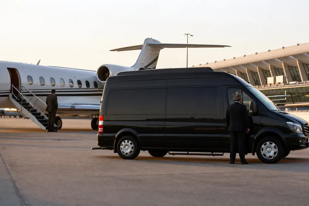 Black Mercedes-Benz Sprinter beside a private jet at the Dulles Jet Center